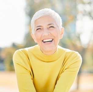 smiling lady outdoors in yellow sweater.